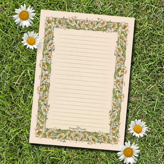 Notebook with floral design on grass with daisies